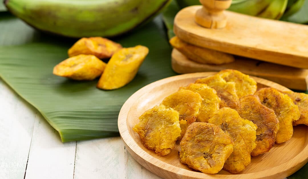 patacones or tostones, fried green plantains on a wooden background, traditional Dominican food
