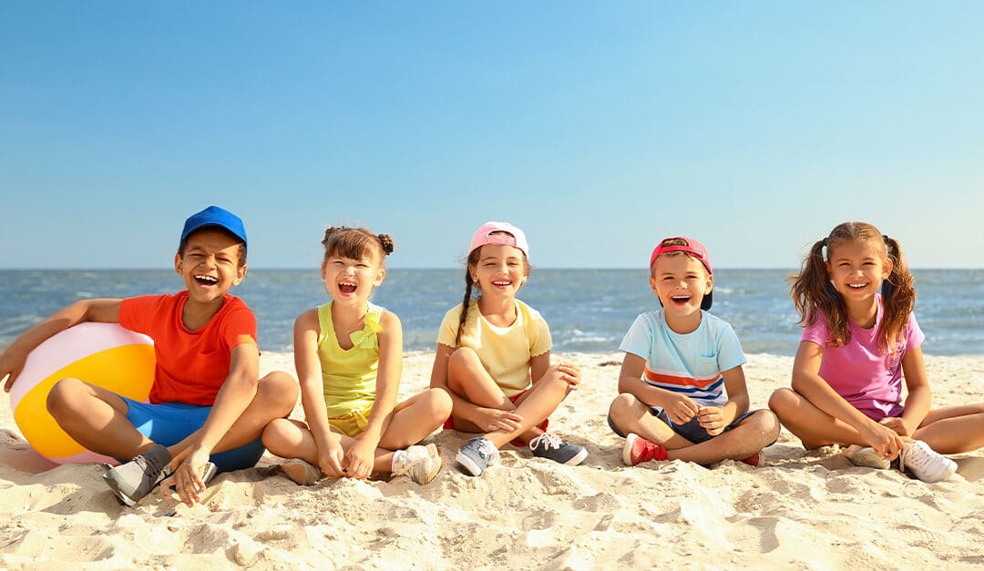 Group of happy children sitting on sand at sea beach