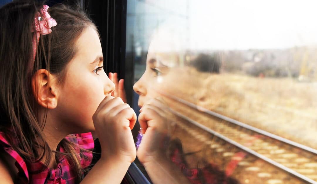 Little girl looking through window as she travels on a train. Spanish Phrases for kids - has viajado