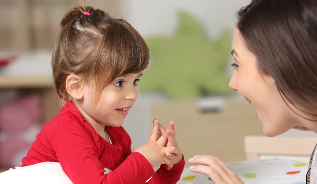 Mother and toddler wearing red shirt playing together on a bed in the bedroom at home, talking and responding in Spanish