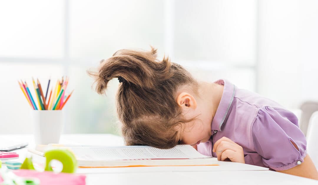 Frustrated young girl resting with her face down on the school book