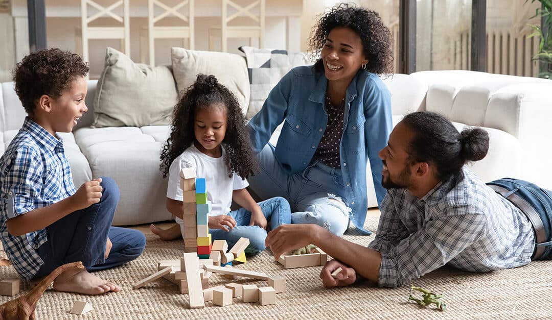 Parents and children playing with blocks on the floor, learning Spanish