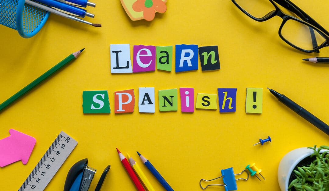 Cutout letters in bright colors spelling "Learn Spanish" on a yellow background with school supplies | Are Spanish Classes Right for My Child Blog