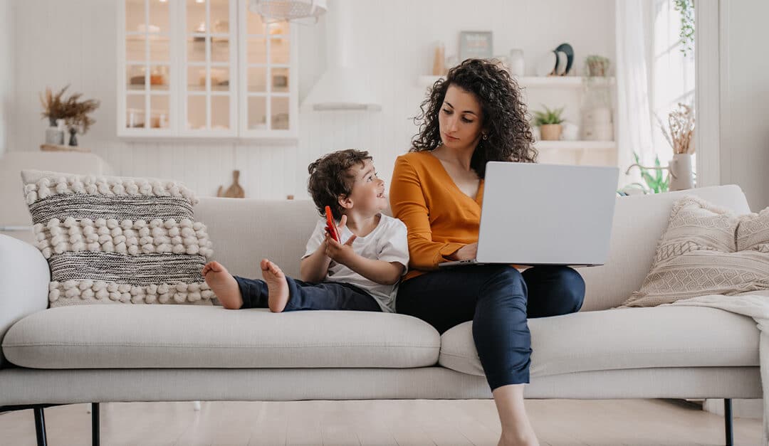 Mom and young son sitting together on the couch, learning Spanish together | Illustrating blog concept of How to Teach Yourself and Your Kids Spanish