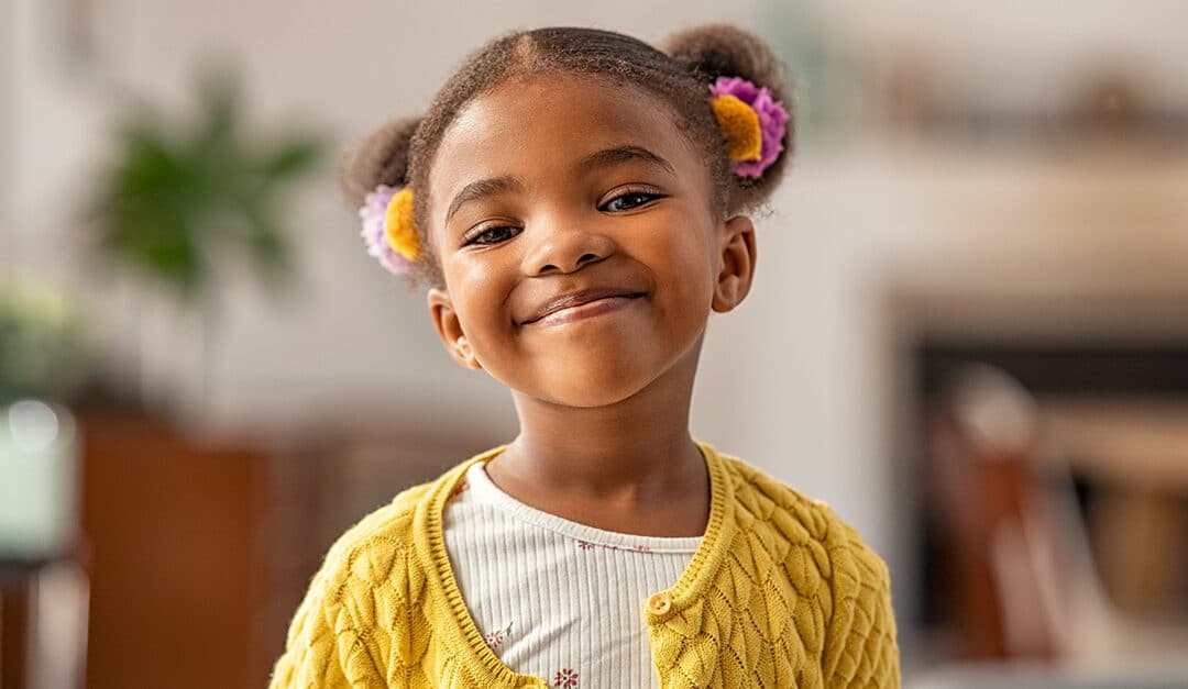 Smiling cute girl with two pony tails looking at camera, illustrating the blog topic Happy Feelings and Emotions in Spanish