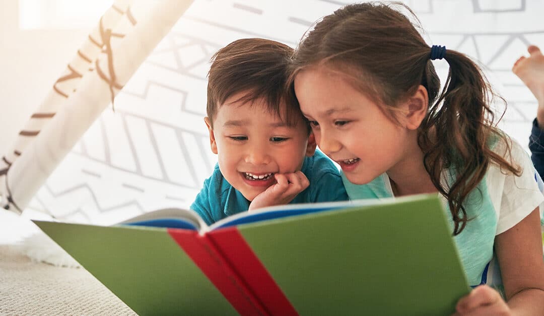 Two small children in an inside tent reading a book together